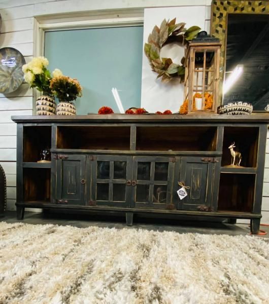 Dark wooden TV console with cabinet doors, decorated with wreaths and lanterns on a fluffy cream rug.