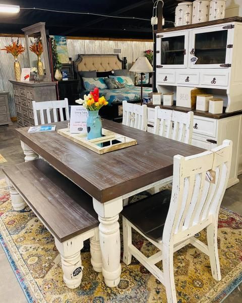 Rustic dining room with a dark wood table, white chairs, and a farmhouse hutch on a patterned rug