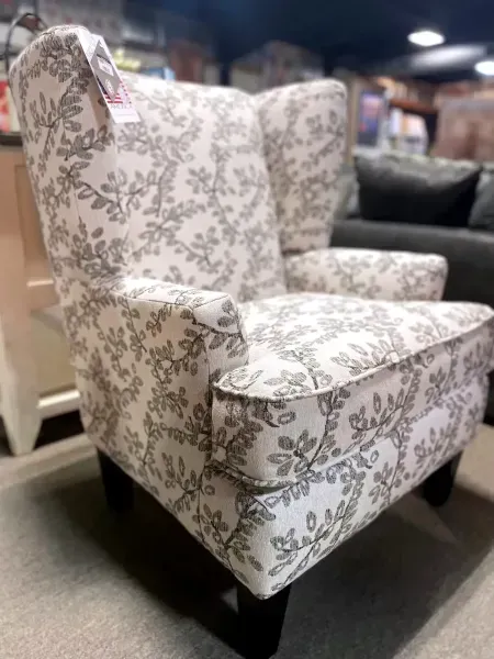 Floral upholstered wingback armchair on a dark base in a furniture store showroom