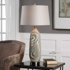 Decorative silver table lamp with white shade on a side table beside stacked books