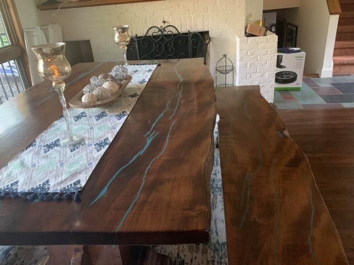 Wooden dining table with a blue resin inlay in a living room, set with a table runner and decor.