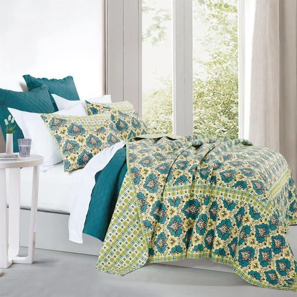 Colorful teal and yellow patterned bedding on a neatly made bed beside a bright window