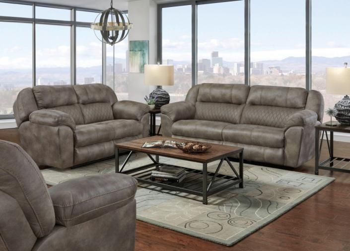 Brown living room set with two loveseats, coffee table, lamp, and city view windows
