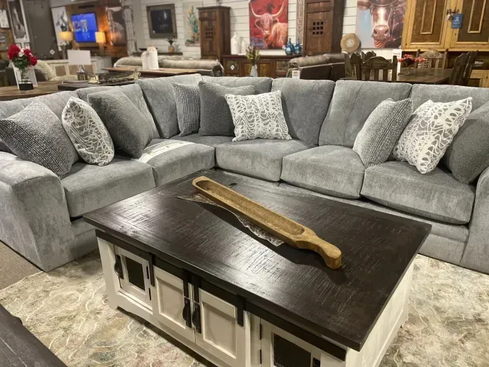 Gray sectional sofa around a dark coffee table in a furniture showroom