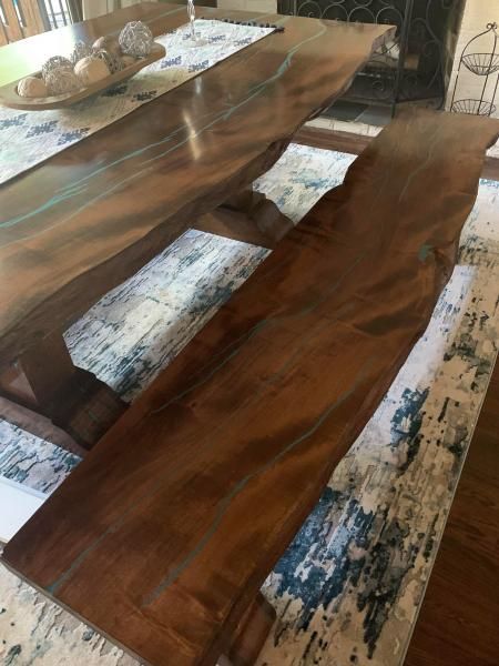 Wooden dining table with benches and a decorative tray centerpiece in a bright room