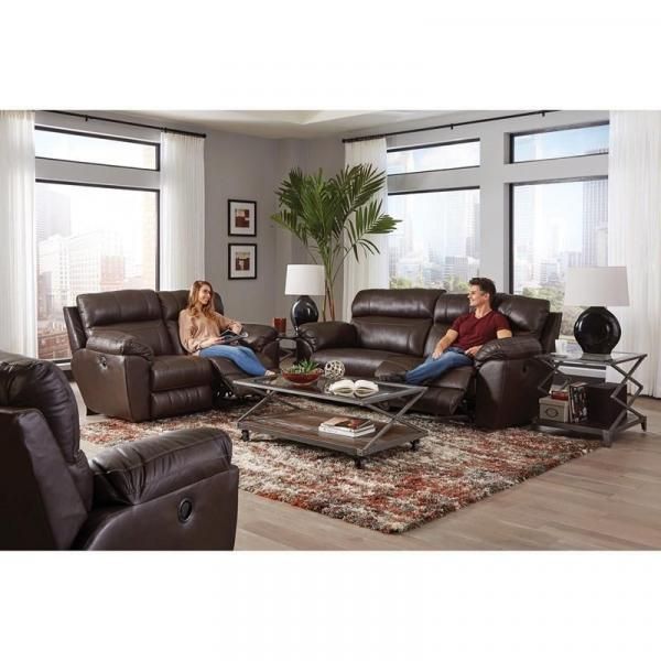 Modern living room with leather sofas, glass coffee table, rug, and two people sitting and relaxing