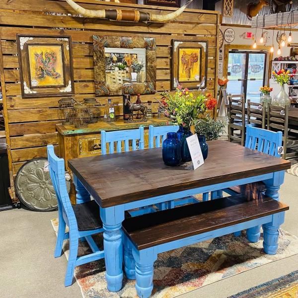 Rustic dining room with bright blue table and chairs against a wood-paneled wall