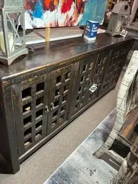Dark wooden cabinet with lattice doors beneath a shelf, holding a blue can and decor in a living room.
