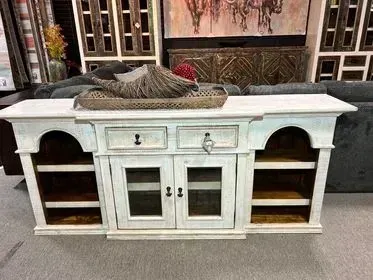 White distressed media console with drawers, cabinet doors, open shelves, and decorative tray on top