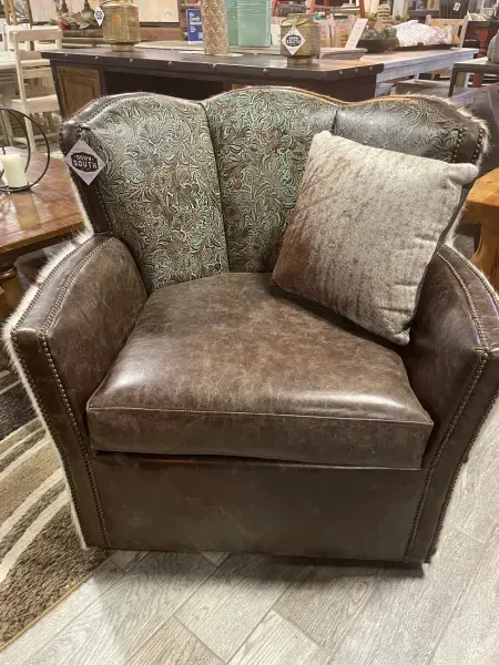 Brown leather armchair with patterned back cushions and a beige pillow in a furniture store.
