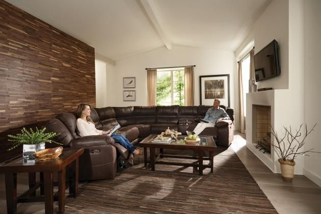 Modern living room with brown sectional sofa, coffee table, fireplace, and wall-mounted TV.