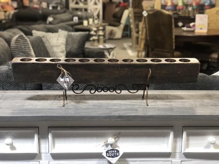 Long rectangular candle holder with multiple tealight openings on a gray cabinet in a furniture showroom
