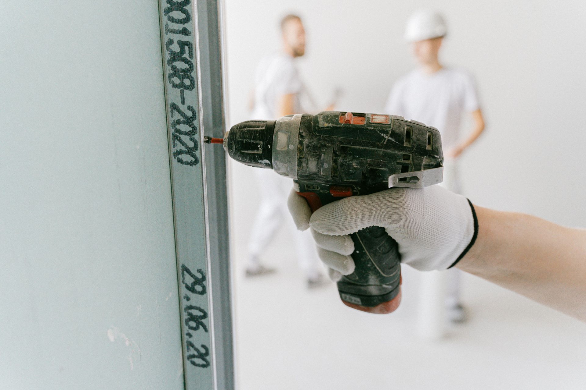 Worker using a putty knife to repair a ceiling in a room with white walls