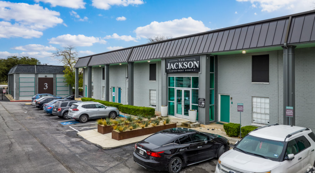 Modern commercial office building with parked cars and a JACKSON sign at the entrance