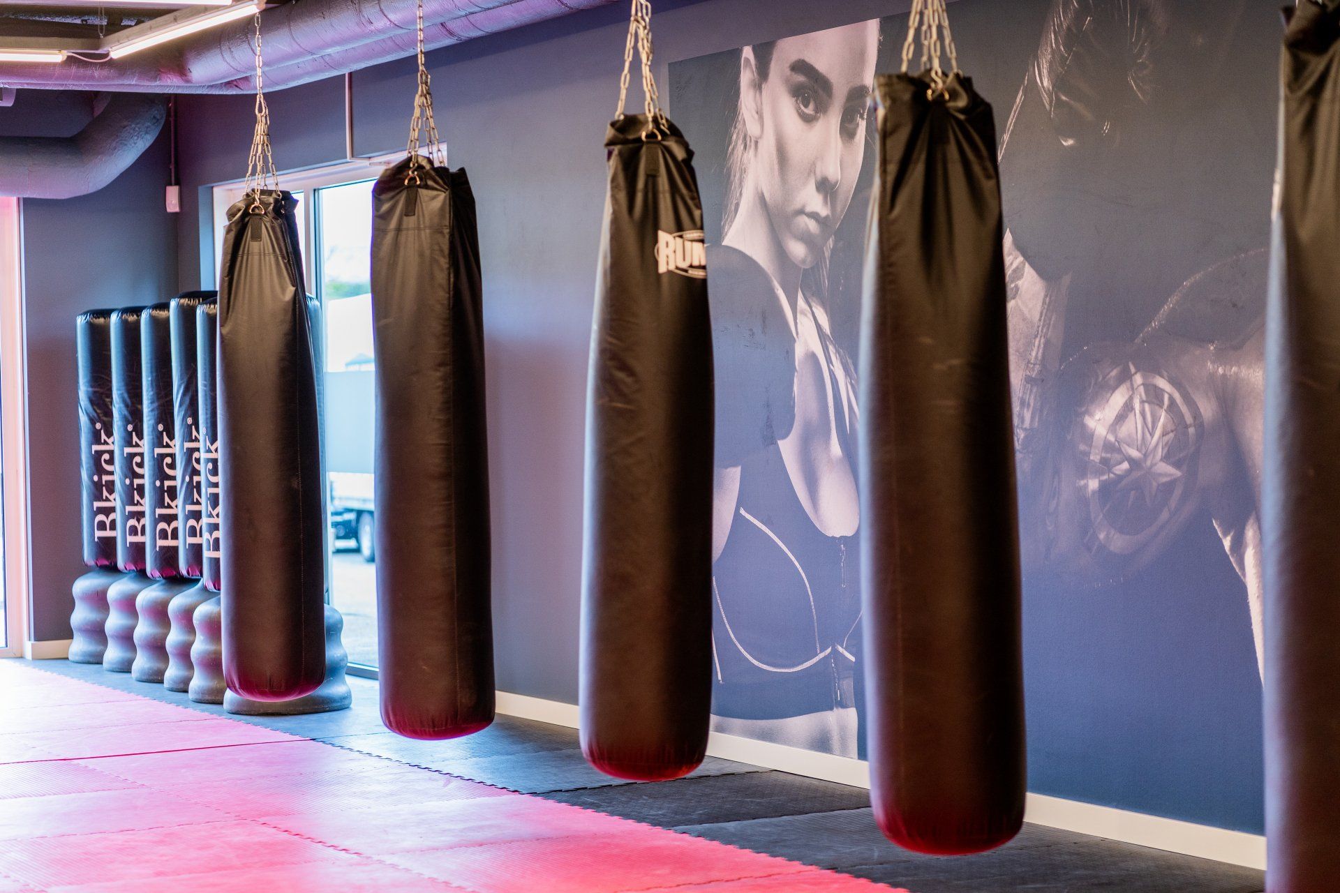 Een rij bokszakken die aan het plafond hangen in een sportschool.