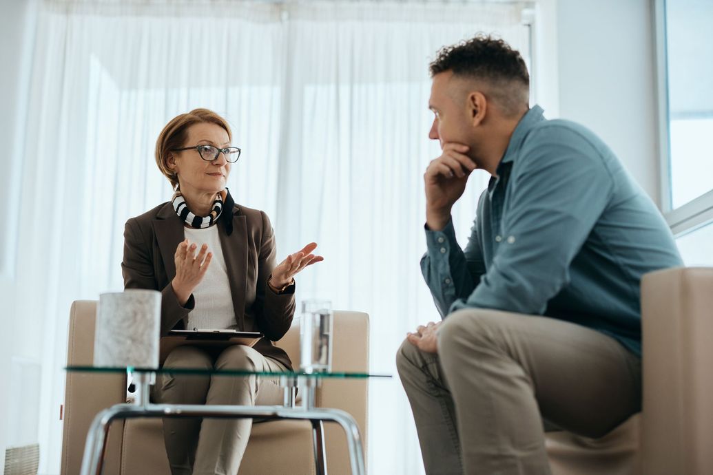 Two people in discussion across a glass table in a bright office setting