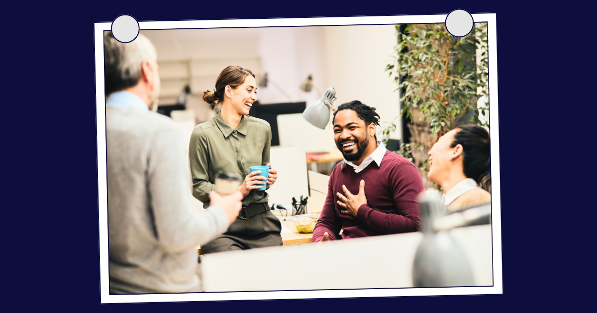 Colleagues chatting and smiling at a casual office gathering around a table with drinks