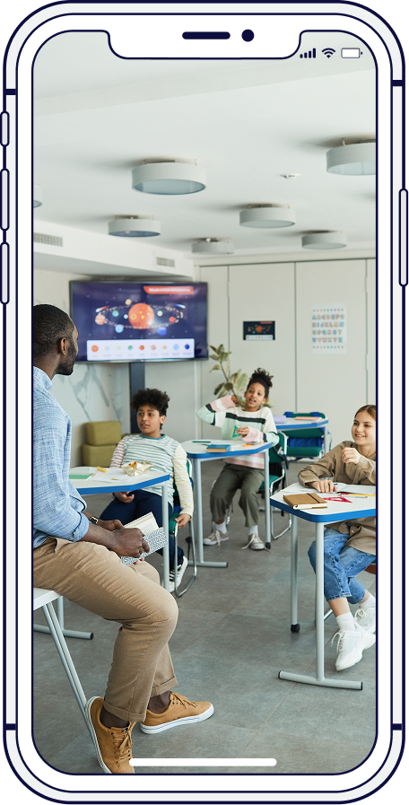 Teacher with students in a classroom, one child raising their hand.