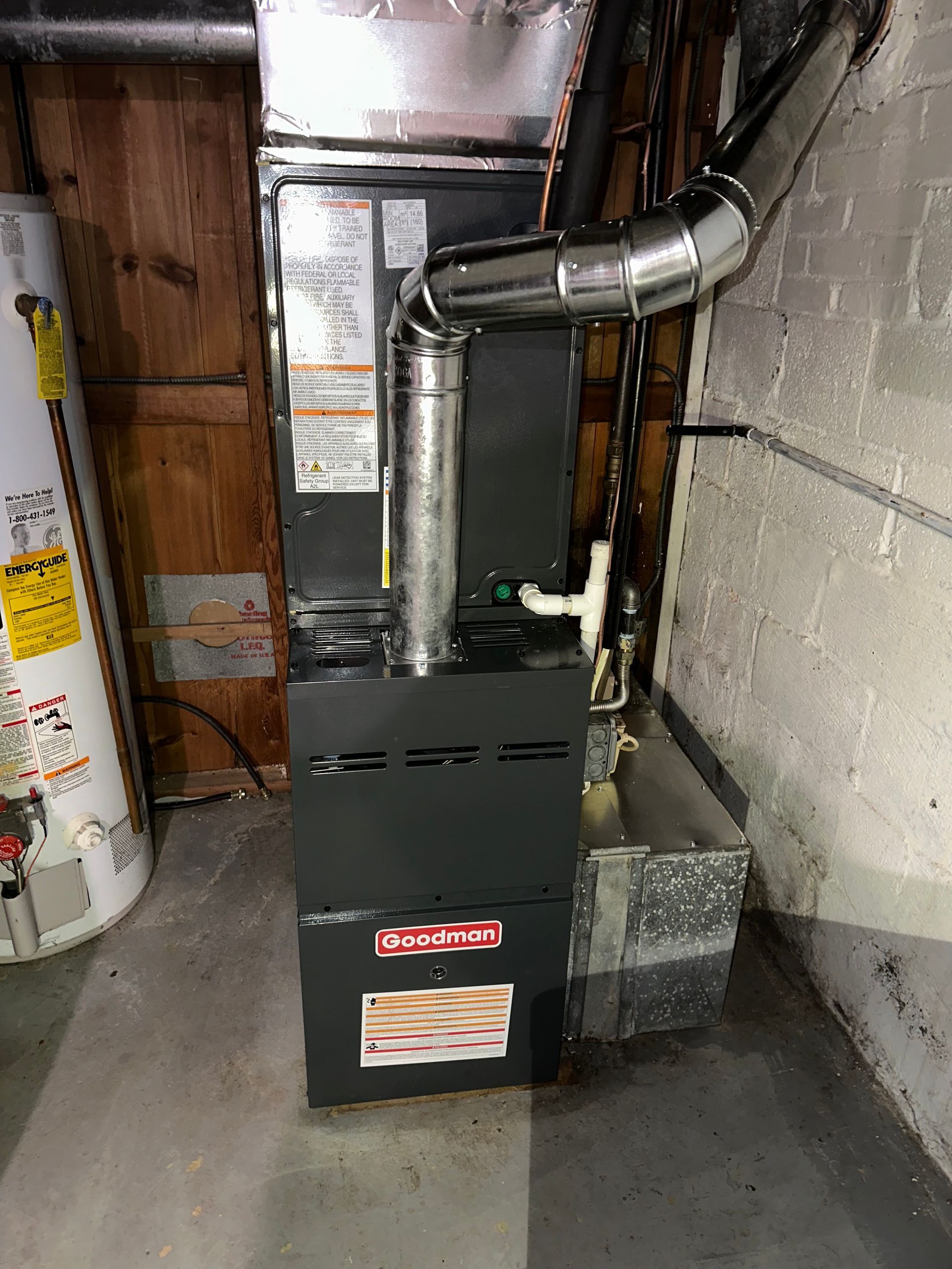 Furnace and water heater in a basement utility area with metal ductwork and concrete floor