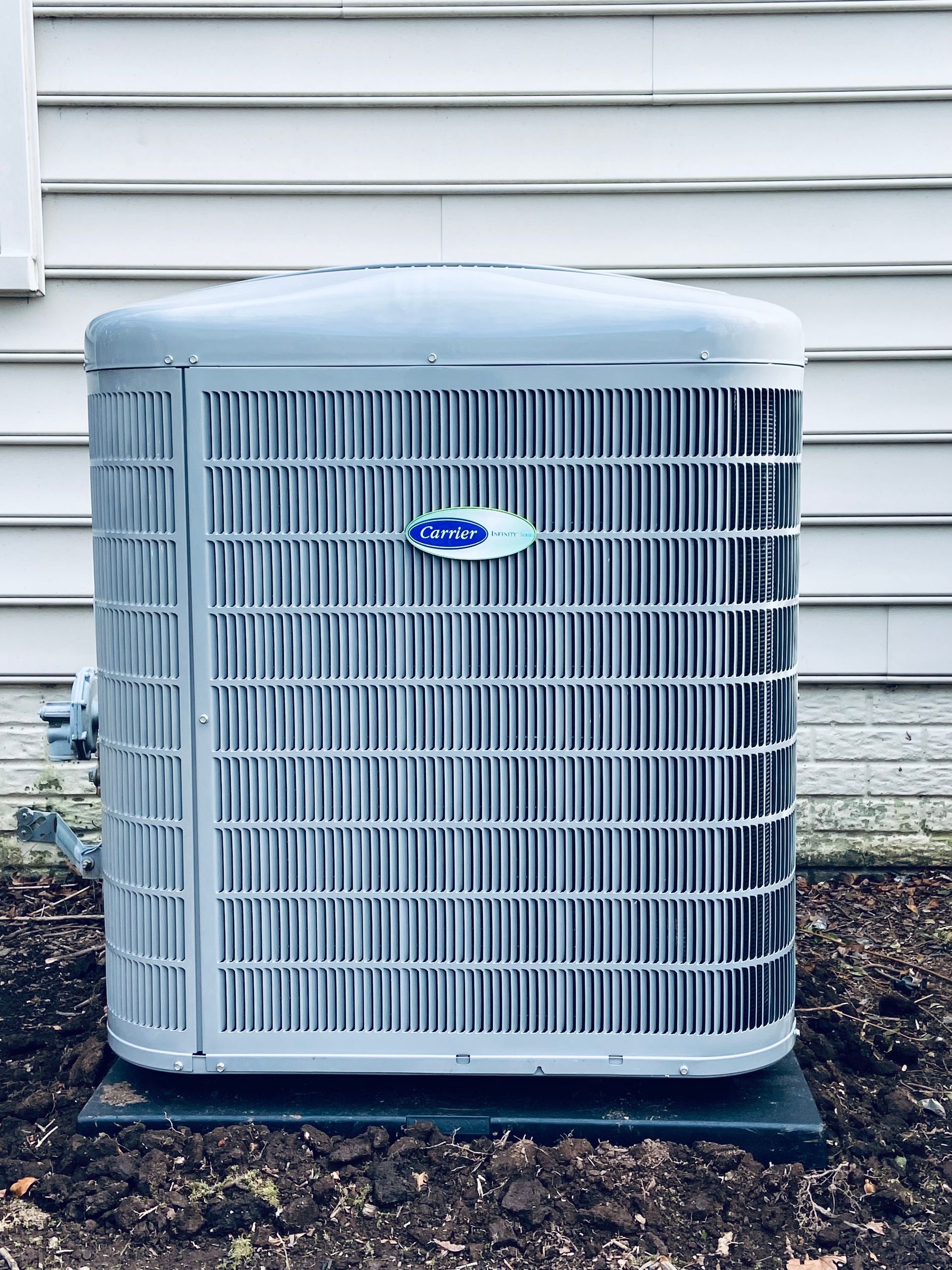 Outdoor gray air conditioning unit beside a house wall with an American Standard logo.