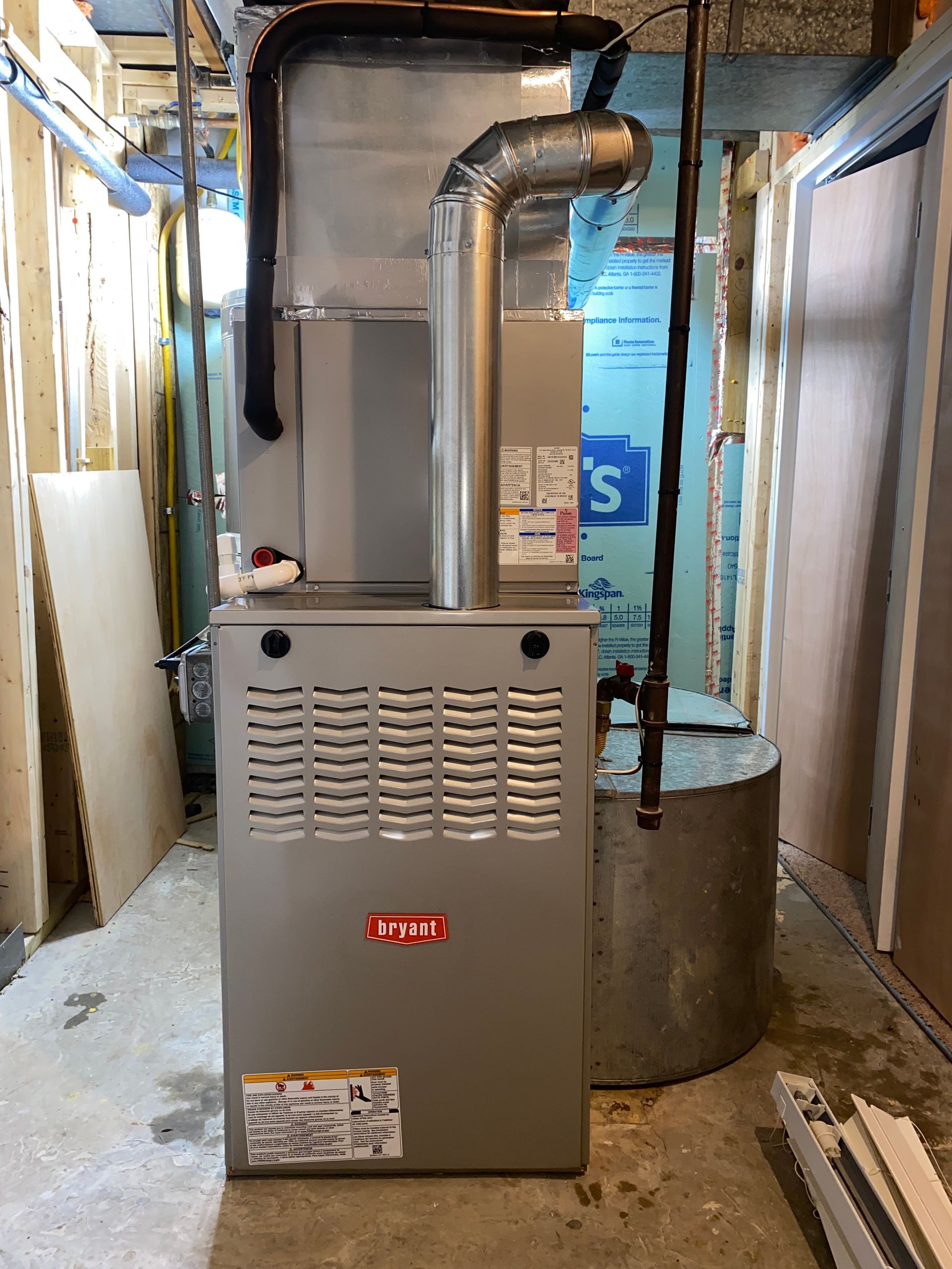 Basement furnace and ductwork in a narrow utility room with unfinished walls