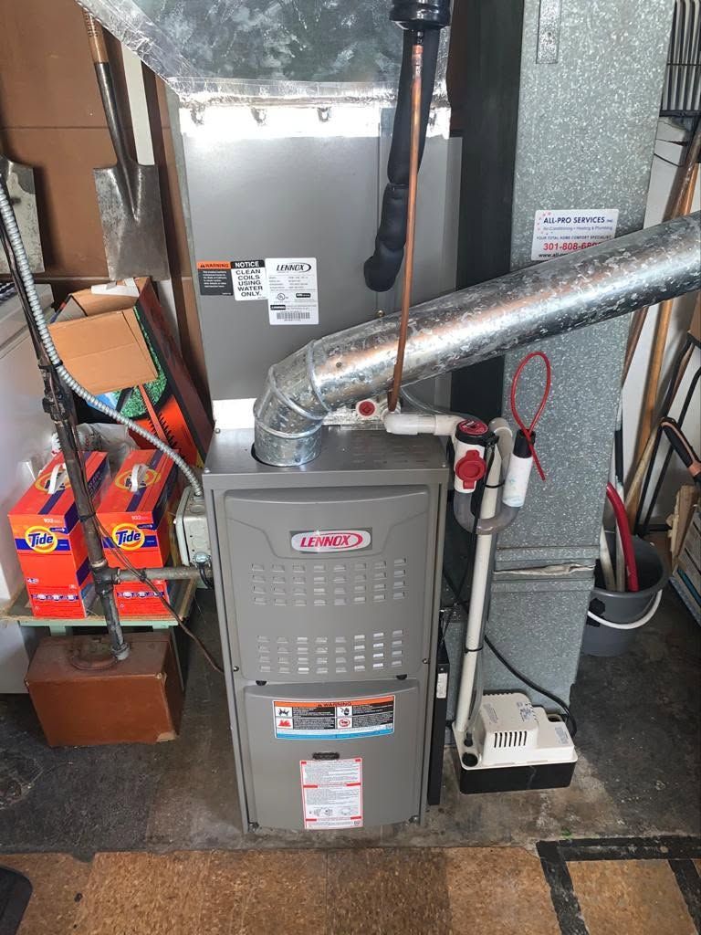 Furnace and ductwork in a basement utility room, with boxes and cleaning items nearby