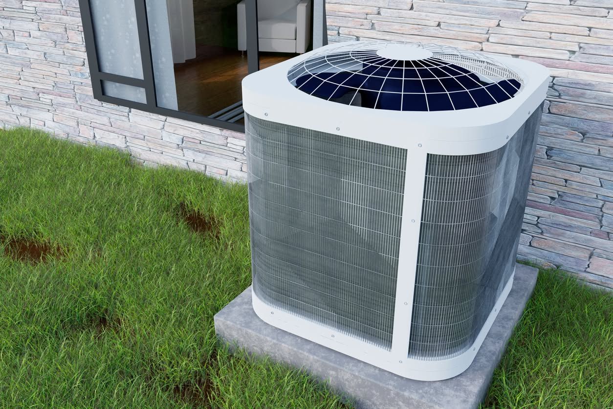 Outdoor air conditioner unit beside a house wall on a grassy lawn