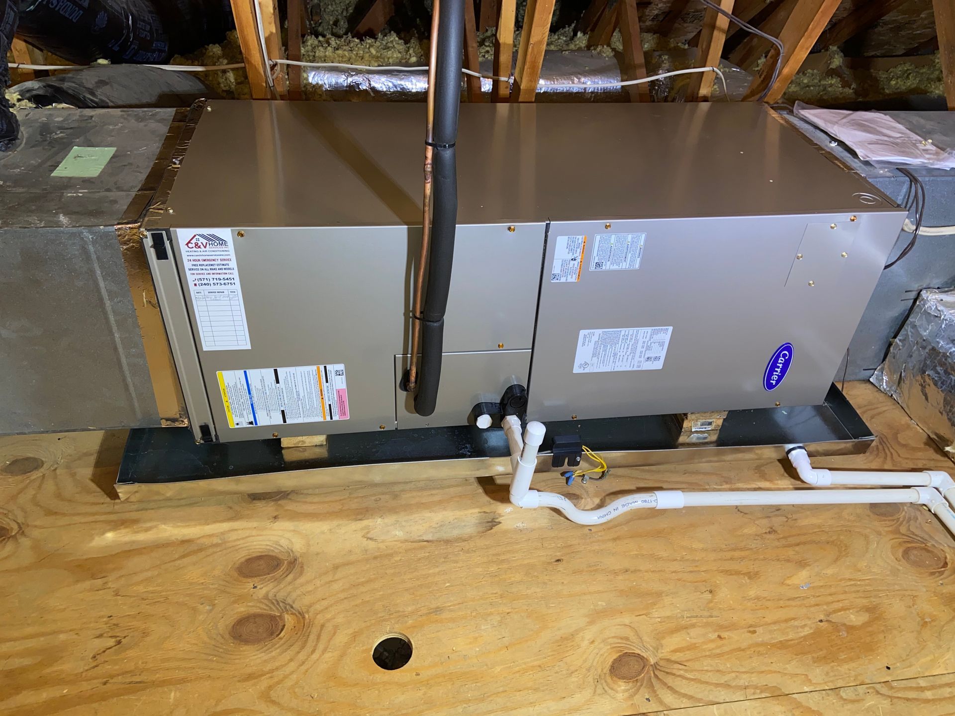HVAC ducting in an unfinished attic with white pipes and wooden floorboards visible below