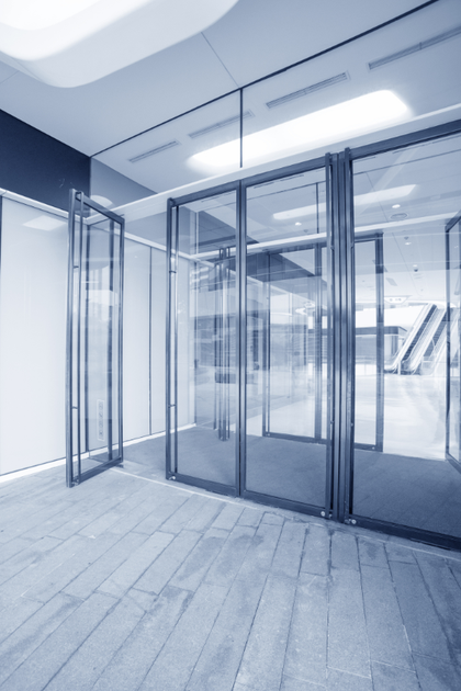 A blue and white photo of an empty building with sliding glass doors.