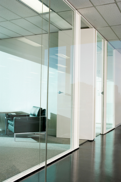 A hallway with glass walls and a black chair