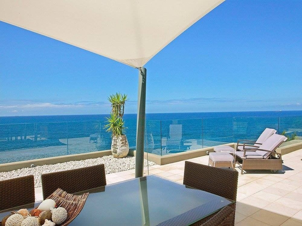 A Table and Chairs on a Balcony Overlooking the Ocean  — Kincumber Glass & Glazing in Kincumber, NSW