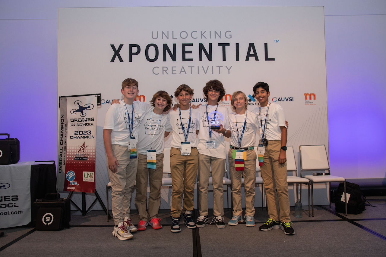 A group of young people are posing for a picture in front of a wall that says unlocking xpoential creativity.