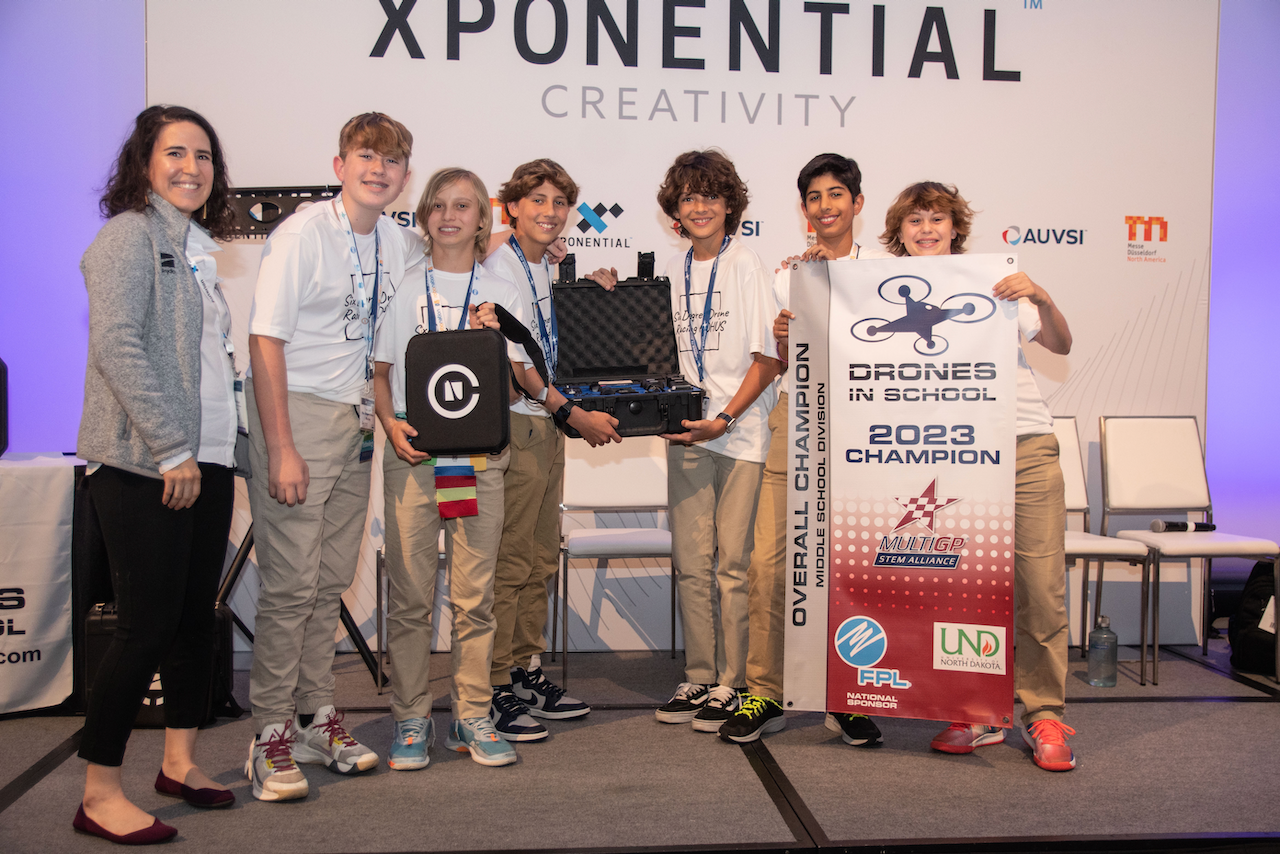 A group of people standing in front of a sign that says xponential creativity