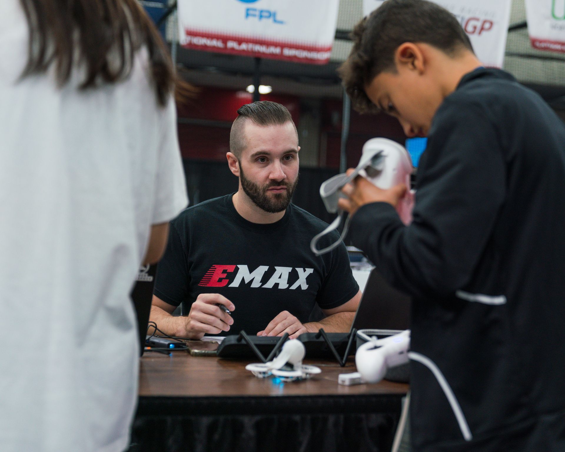 A man wearing a emax shirt is sitting at a table