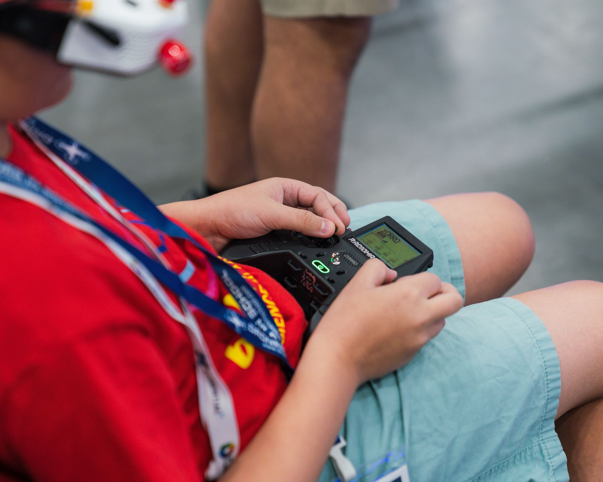 A young boy wearing a red shirt and blue shorts is playing a video game.
