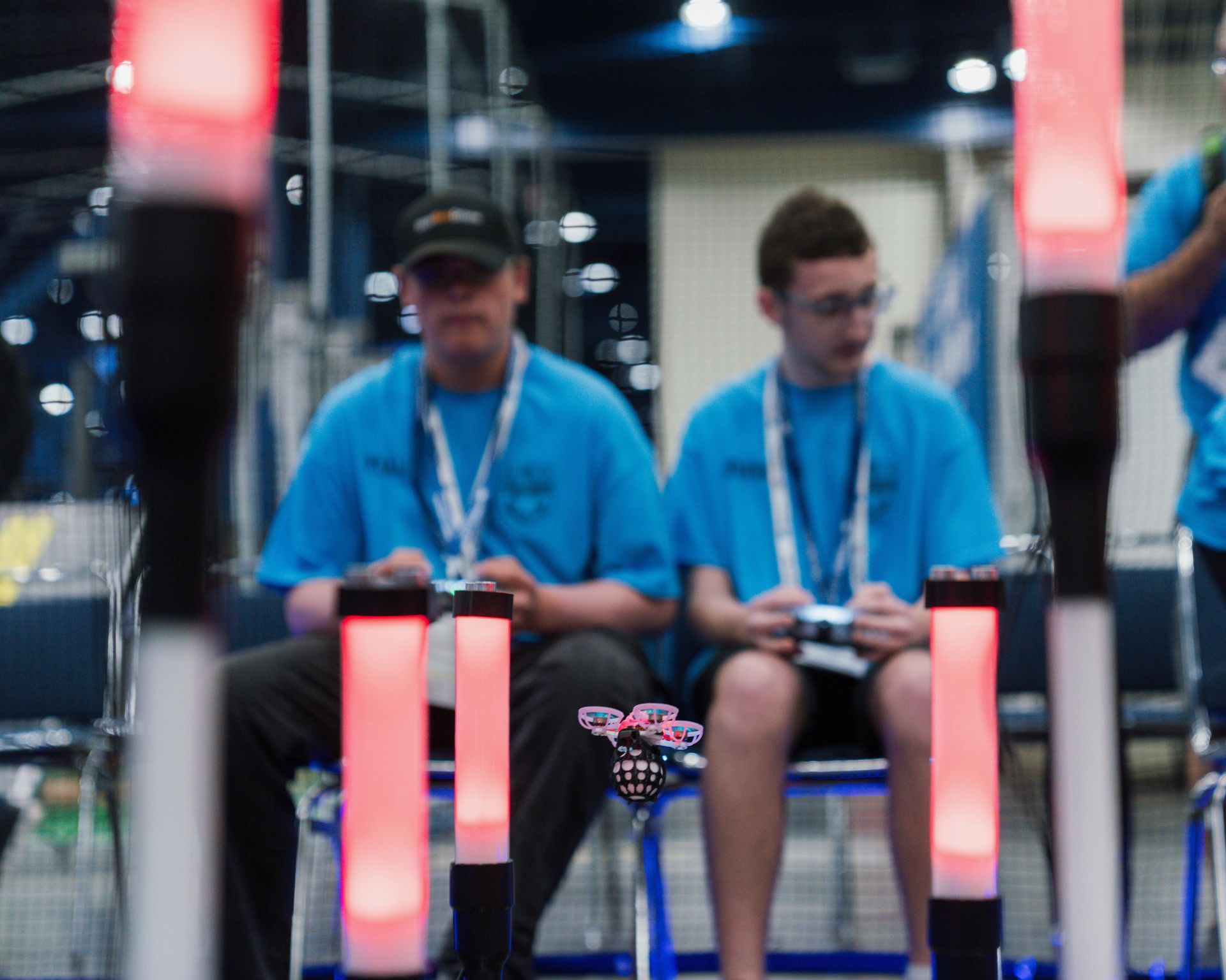 Two men in blue shirts are sitting in front of red lights.