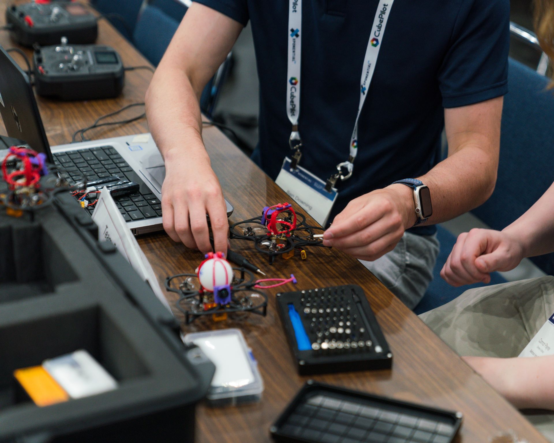 A man with a lanyard around his neck is working on a drone