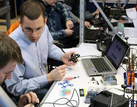 A group of men are working on a project in front of a laptop computer.
