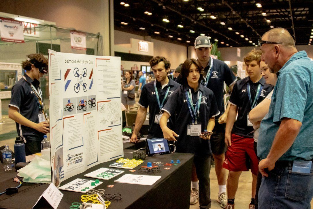 A group of people are standing around a table looking at a poster.
