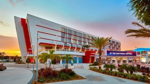 A large white and red building with palm trees in front of it.