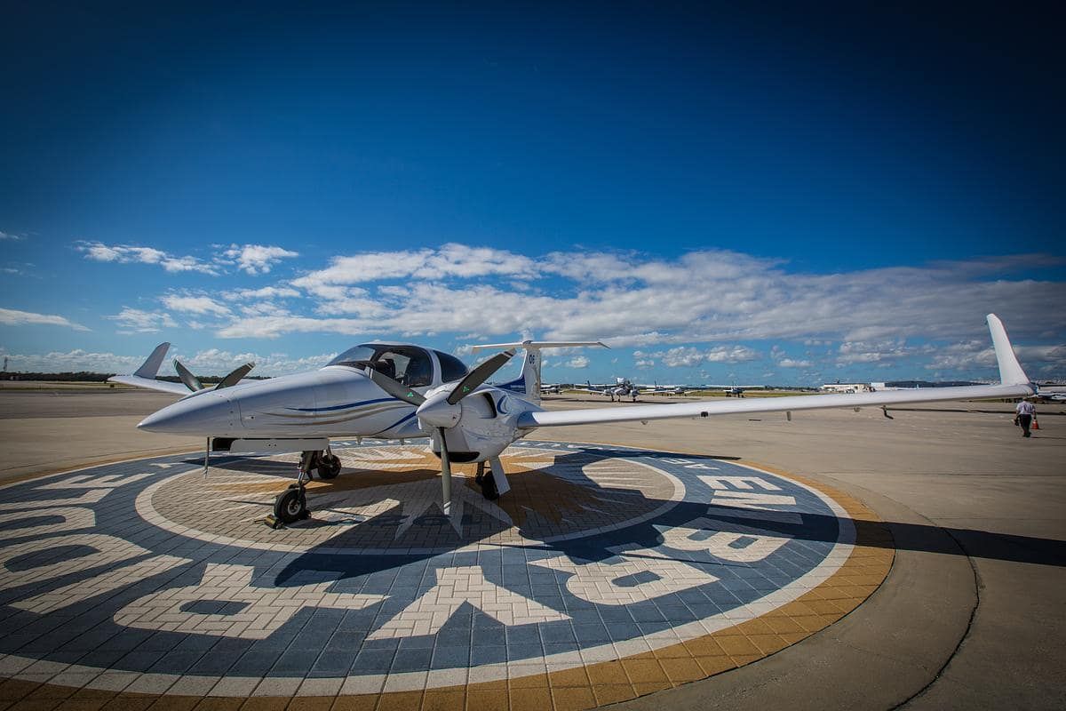 A small plane is parked on a runway in front of a sign that says ' sky ' on it.