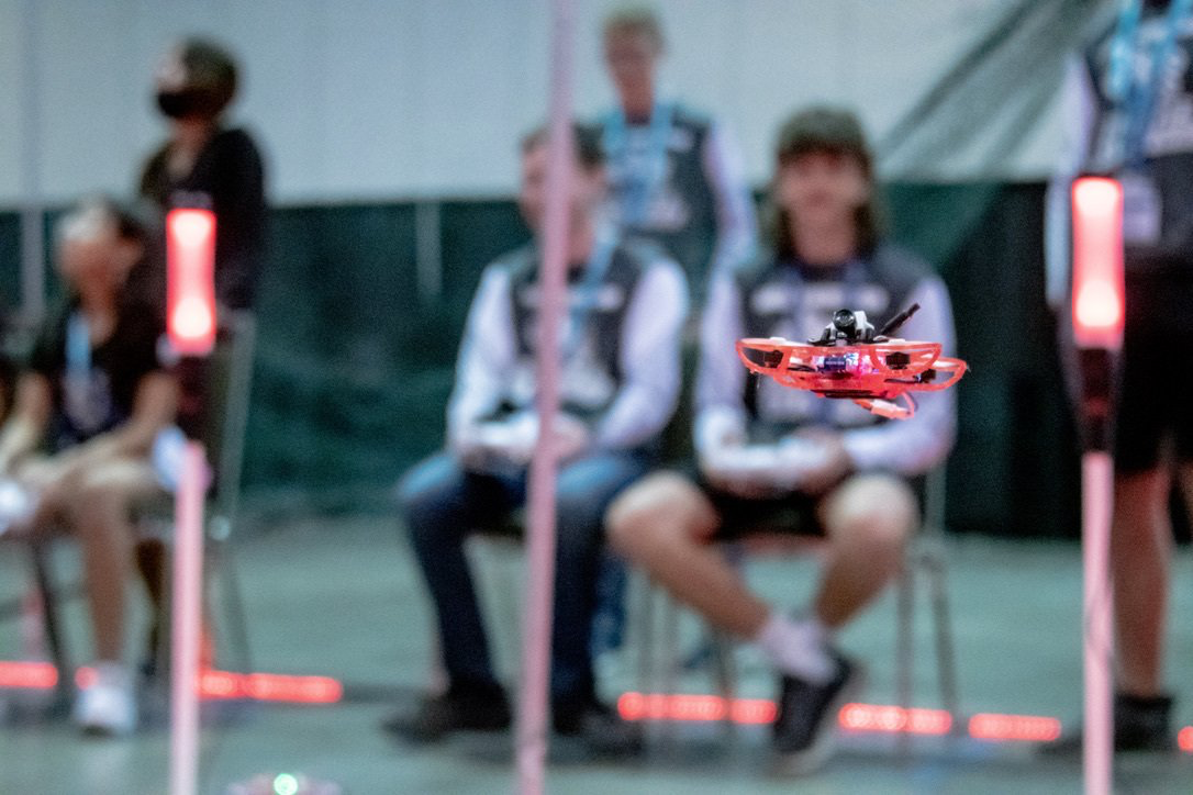 A group of people are sitting in chairs watching a drone fly.