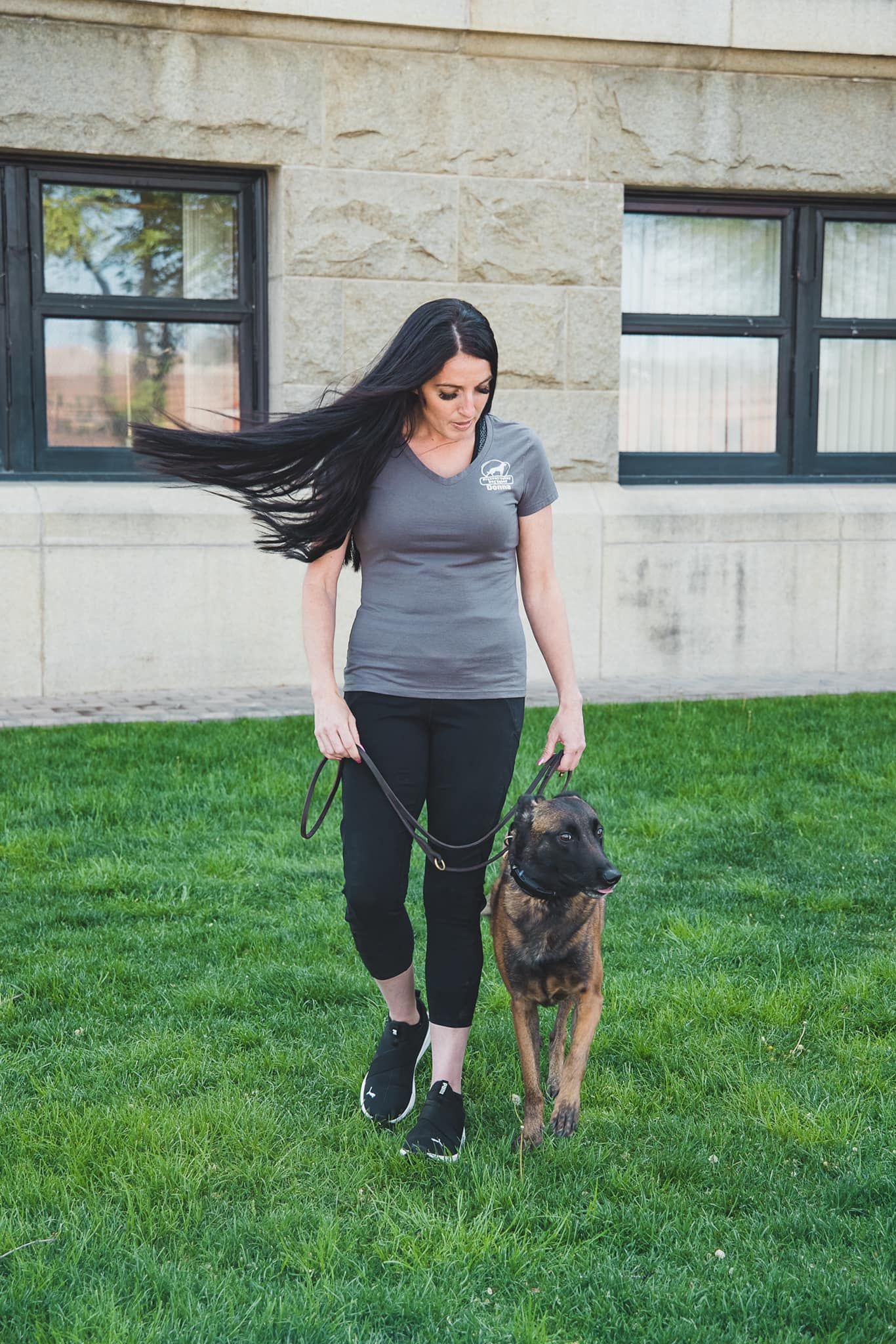 a woman walking a dog on green grass