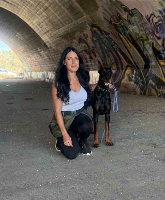 a woman hugging a dog and looking at the camera