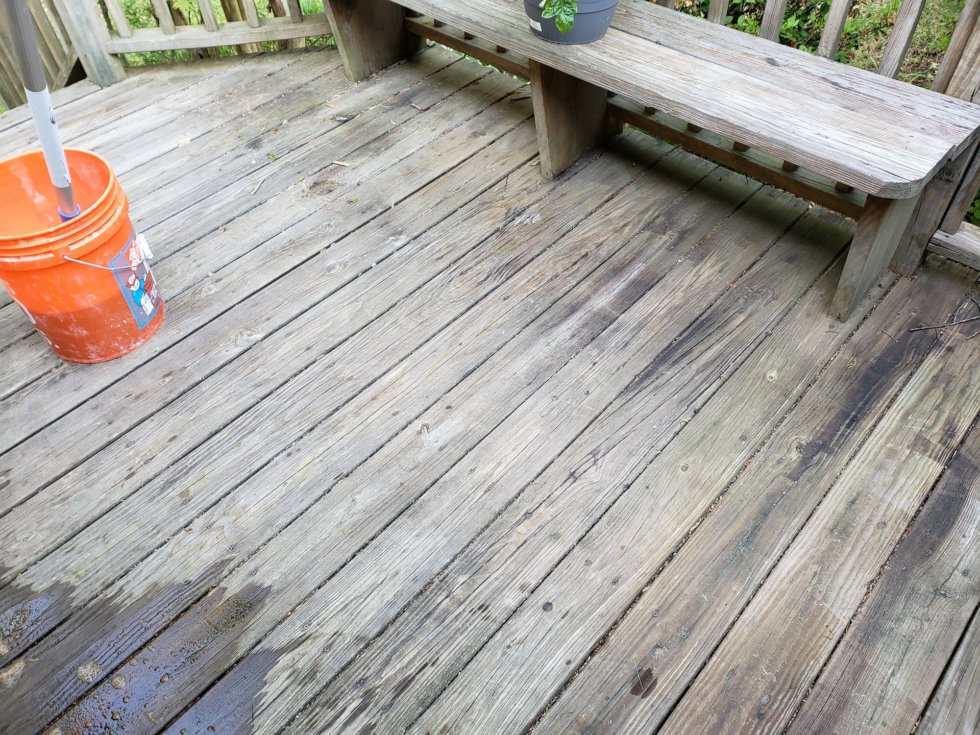 A wooden deck with a bench and a bucket of water on it.