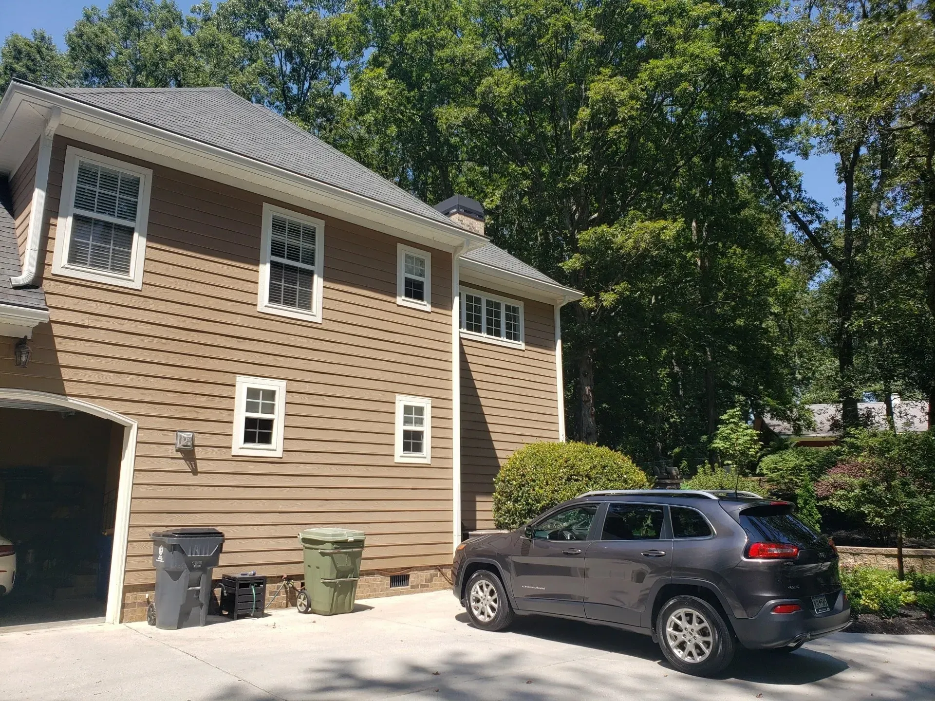A jeep is parked in front of a house on a sunny day.