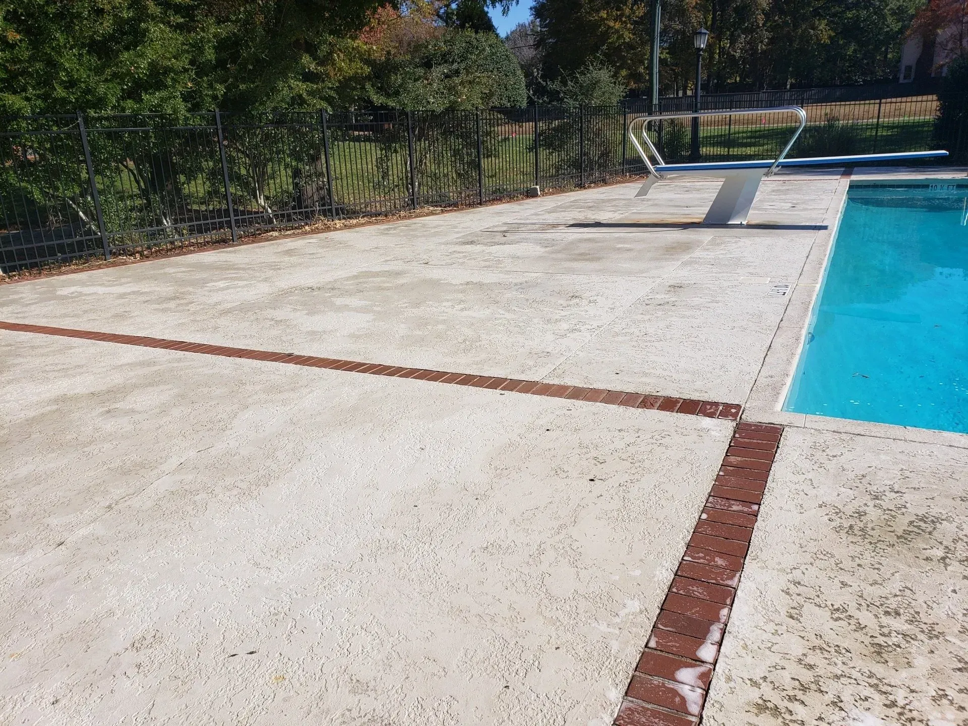 A swimming pool with a concrete patio in front of it