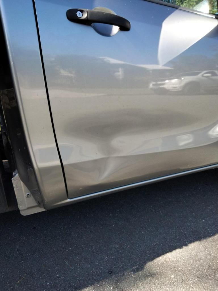 A Silver Car with Dent Is Parked on The Side of The Road — Dent Repair Specialist in Caboolture, QLD