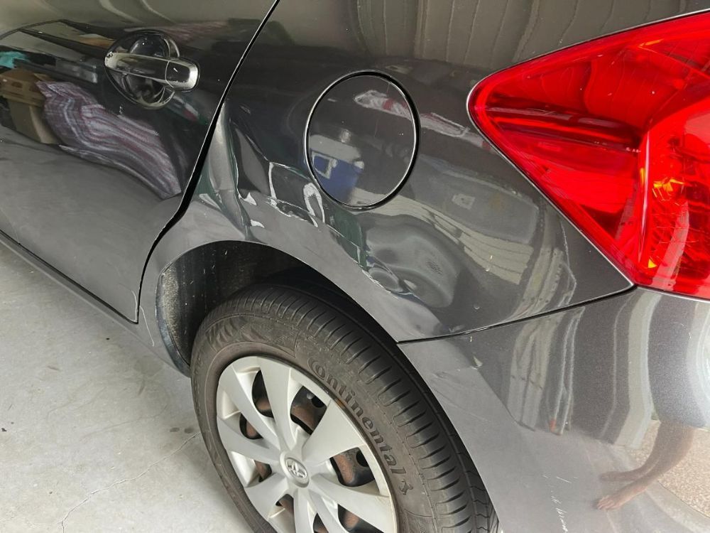 A Dented Gray Car with A Red Tail Light Is Parked in A Garage — Dent Repair Specialist in Caboolture, QLD