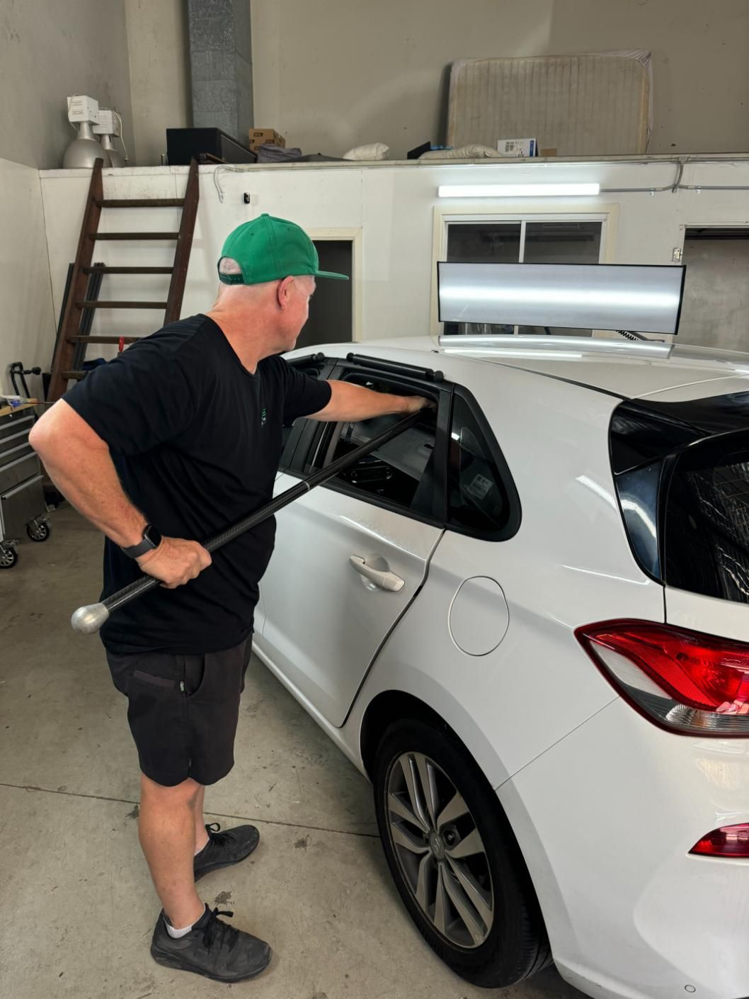 A Man in A Green Hat Is Standing Next to A White Car — Dent Repair Specialist in Kunda Park, QLD